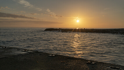 Breakwaters on the seashore in the rays of the setting sun at sunset. Autumn seascape