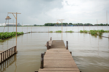 Fototapeta premium River Repose: Wooden Pier Extending into Tranquil Chao Phraya River in Thailand. 
