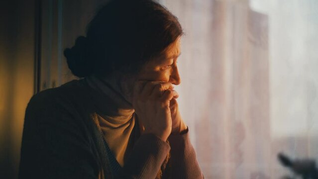 Sorrowful senior woman sitting alone, thinking about financial problems, poverty