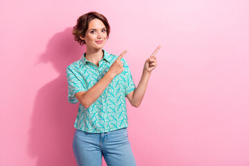 Photo of cute promoter lady direct fingers advertising empty space mockup wear printed shirt jeans isolated pink color background