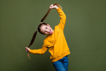 Photo of funky girl holding ponytails wear yellow pullover jeans stick out tongue fooling around...