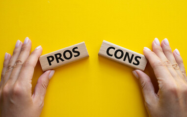 Pros vs Cons symbol. Concept word Pros vs Cons on wooden blocks. Businessman hand. Beautiful yellow...