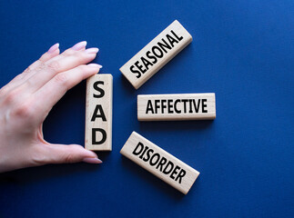 Sad - Seasonal Affective Disorder symbol. Wooden blocks with words Sad. Businessman hand. Beautiful...