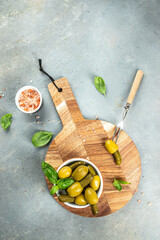 olives with pickled cucumbers in a bowl on a light background top view. place for text