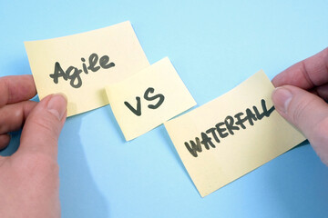 waterfall vs agile paper task on blue background, software development methodologies concept
