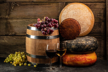 Glass of wine, cheeses and grapes on a wooden background, A head of hard cheese