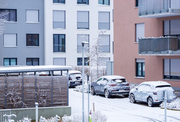 Cars covered with snow are parked in a residential complex. Winter in the city, houses, buildings,...