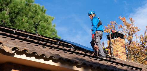 Man installing solar panels on the roof of a house