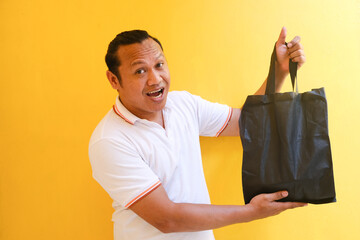 asian man in white shirt very happy holding black shopping bag