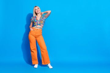 Portrait of gorgeous adorable girl wear stylish shirt orange pants hand in pocket arm on neck isolated on vivid blue color background