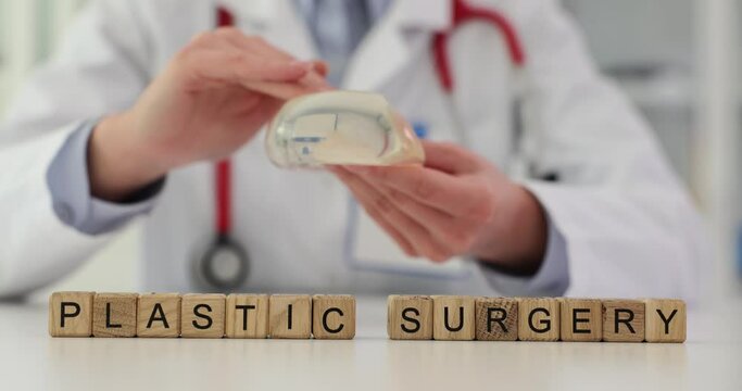 Experienced plastic surgeon holds silicone breast implants in clinic