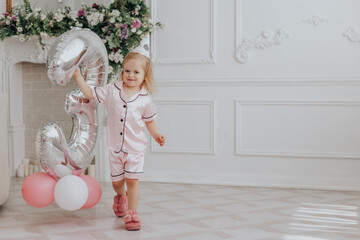 Blonde girl celebrates her 3th birthday in pink pajamas