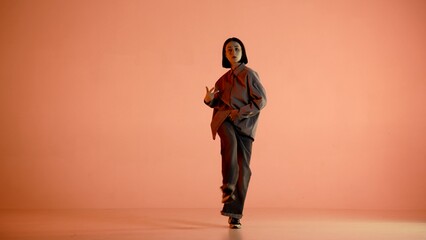 In the picture on an orange, light background. Dances young, beautiful girl. Demonstrates dance...