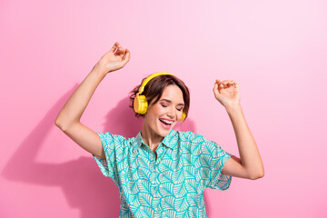 Photo of carefree overjoyed lady listen favorite song headphones dancing isolated on pink color...