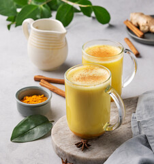 Turmeric golden milk latte with spices and honey. Detox, immunity boosting, anti-inflammatory, healthy, cozy drink in a glass cup on a light background