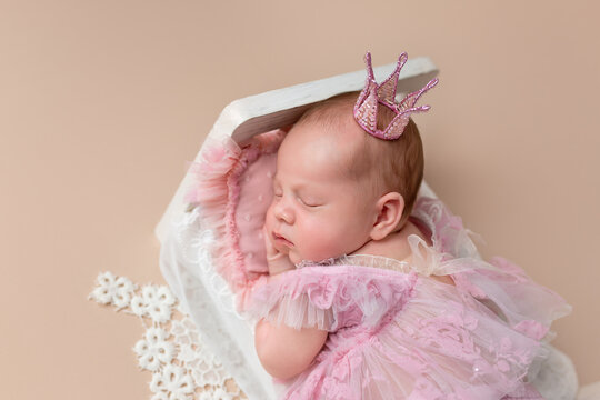 Cute newborn baby wearing a dress and crown. Little Princess. Newborn girl in a crib. Newborn's first photo session