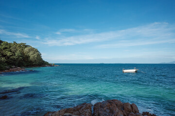 Outdoor scenery view of small boat 
 anchoring and sea waves with clear water crushing over the...