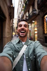 Foto op Plexiglas Happy vertical selfie of a young caucasian man in an old town of Barcelona. Male tourist taking a self portrait using smartphone to post it on social media, © Gigi Delgado