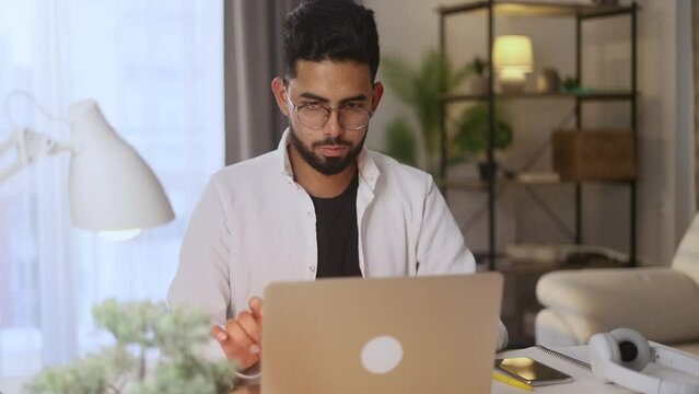 Positive tired young man feels satisfied with distance remote work well done at home workplace Calm handsome male relax after hard working day on laptop computer indoors