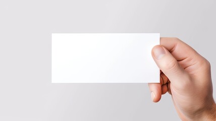 Obraz premium a man's hand holding a blank, simple white business card design mockup, the absence of text and the potential for business branding against a light background.