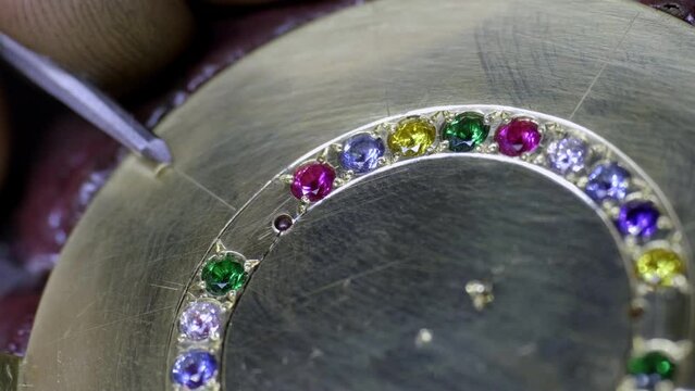 Hand Engraving lines into a golden pendant, fitted with colorful cristals, workshop 