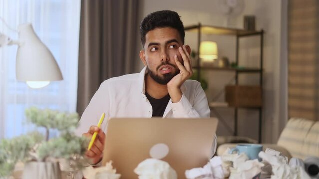 Portrait of young handsome man student or freelancer thinks questioningly and finding solution and looking at camera at home Idea pointing forward index finger concept