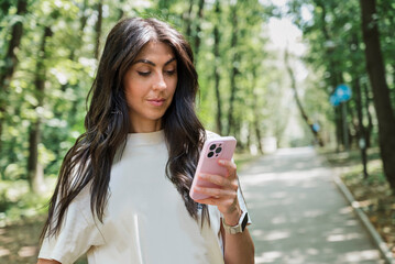 Beautiful Brunette Woman using her phone in the summer park