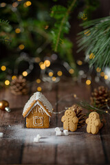 Gingerbread little houses decorated with icing standing on the table among Christmas pine and lights  