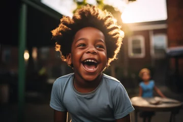 Foto op Canvas Black child laughing at loud, outdoors in school playground, sunlight in the hair, playing, wearing a tshirt, intense expression playful smile, african american boy, thrilled, classmate, happy, warm © Oliver Evans Studio