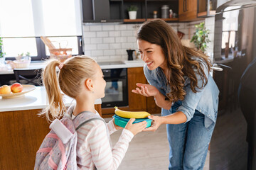 cute girl, caring young mother, preparing, school, giving, fruit snack, lunch box, education, parenting, morning routine, school preparation, healthy snack, back to school, motherhood, childhood, care