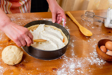 Chef puts cottage cheese in a mold to prepare apricot cheesecake.