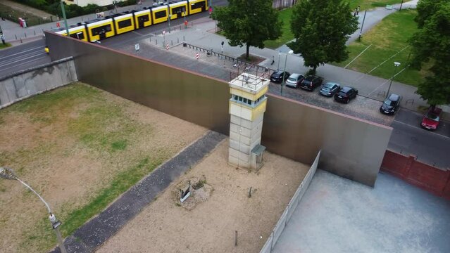 High angle view of historic border from cold war era. Watchtower and walls in Berlin Wall Memorial. Modern urban borough surrounding landmark. Berlin, Germany