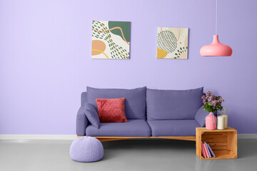 Beautiful lilac flowers with soft sofa in interior of room