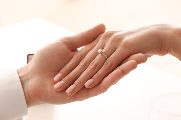 Engaged couple holding hands at table, closeup