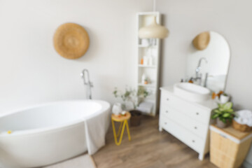 Interior of light bathroom with white sink, bathtub and shelving unit, blurred view