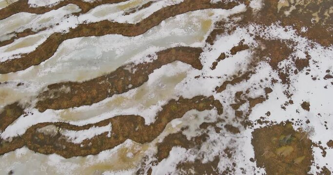 Aerial abstract view of a swamp in spring with snow still on the ground.
