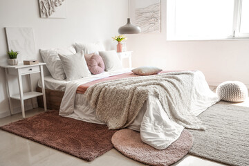Fototapeta na wymiar Cozy bed with white blanket and pillows in interior of light bedroom