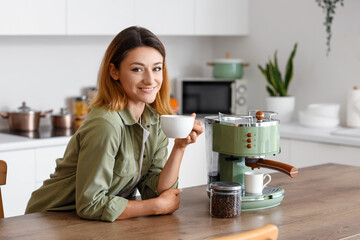 Young woman with cup of hot coffee in kitchen