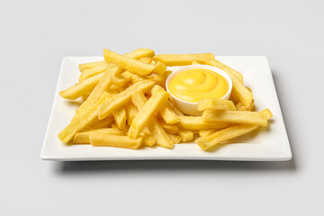 Plate with golden french fries and cheese sauce on grey background, closeup