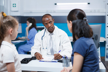 In hospital office, doctor consults with a caucasian woman and her daughter, discussing a medical condition, and providing advice and treatment options. Professional and caring atmosphere.