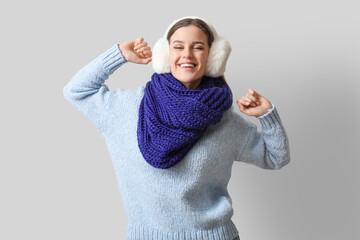 Happy young woman in winter clothes on light background