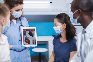 Detailed image of healthcare professionals using a tablet to explain to the female patients about...
