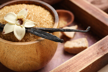 Bowl with aromatic vanilla sugar, flower and sticks on table