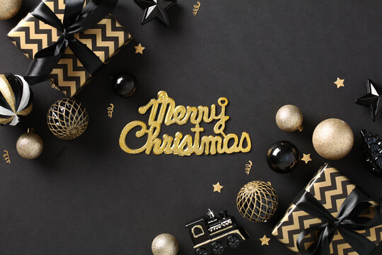 Merry Christmas greeting card with gift boxes and gold baubles on black background. Flat lay, top view