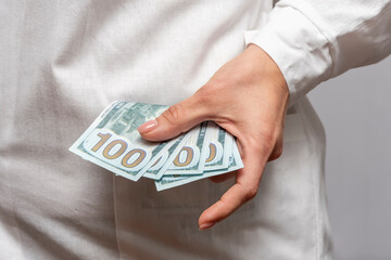 A woman doctor takes out a pack of one hundred dollar bills and a doctor's coat from her pocket. ...