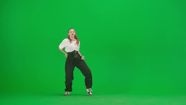In the frame on a green background, chromakey. A young, slender, beautiful girl is dancing. She demonstrates various dance moves in the direction of jazz funk. She is rhythmic, plastic. General plan