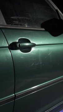 Night frame from the side of the green car that includes the door and the handle and orbits around it