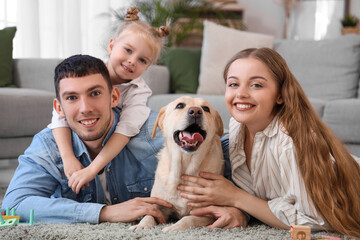 Happy family with Labrador dog lying on floor at home