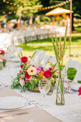 Enchanting Bohemian Table Scape: Long Table with Colorful Flowers, String Light Bokeh, and Scenic Summer Ambiance
