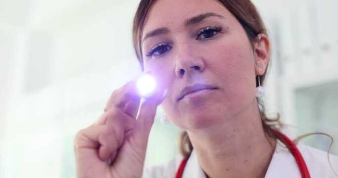 Portrait of female surgeon doctor with flashlight in hand